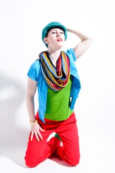 Young woman with black straight hair wears colorful mixed clothes and stands in front of a white background.