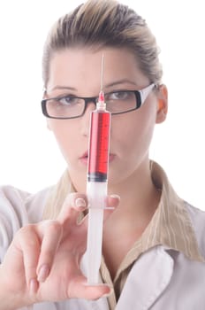 Attractive young doctor with blond hair wears a white coat and holds a large syringe with a red liquid in front of the camera,exposed against a white background.