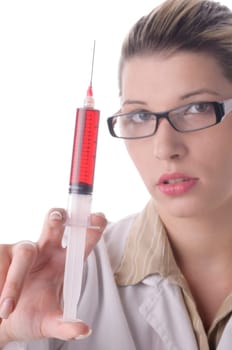Attractive young doctor with blond hair wears a white coat and holds a large syringe with a red liquid in front of the camera,exposed against a white background.