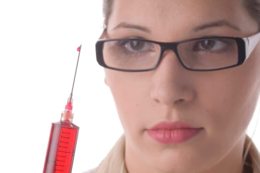 Attractive young doctor with blond hair wears a white coat and holds a large syringe with a red liquid in front of the camera,exposed against a white background.