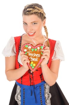 Young attractive woman with blond hair and pigtails wears a colorful dirdl dress and holds a gingerbread heart with the inscription 'Naughty Beast' in her hand,exposed against a white background.