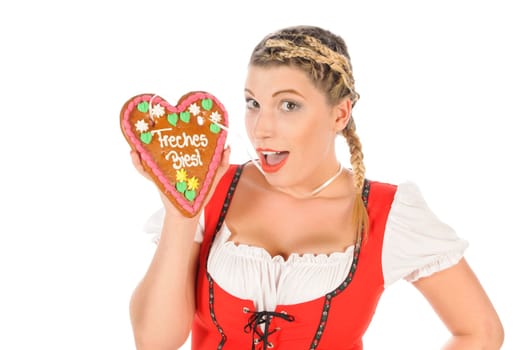 Young attractive woman with blond hair and pigtails wears a colorful dirdl dress and holds a gingerbread heart with the inscription 'Naughty Beast' in her hand,exposed against a white background.