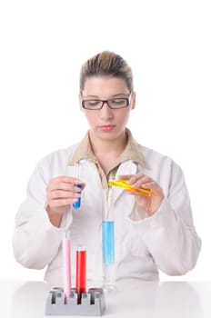 Attractive young chemist with blond hair and glasses wears a white coat and pours various colored chemicals together in test tubes,exposed against a white background