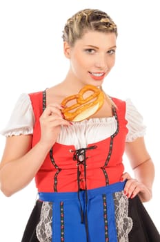 Young attractive woman with blond hair and braids wears a colorful dirdl dress and holds a pretzel in her hand,exposed against a white background.