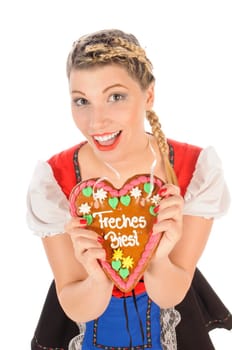 Young attractive woman with blond hair and pigtails wears a colorful dirdl dress and holds a gingerbread heart with the inscription 'Naughty Beast' in her hand,exposed against a white background.