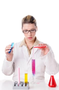 Attractive young chemist with blond hair and glasses wears a white coat and pours various colored chemicals together in test tubes,exposed against a white background