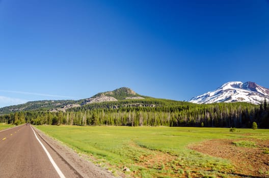 Highway passing next to a forest and South Sister mountain near Bend, Oregon