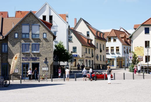 Waren,Mecklenburg Vorpommern/Germany – June 09,2013: People stand in the old town of Waren and look after a passing red convertible on June 9,2013.