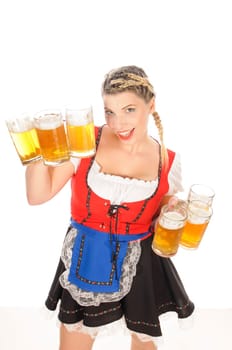 Young attractive woman with blond hair and braids wears a colorful dirdl dress and holds several full beer mugs with freshly tapped beer in her hand,exposed against a white background.