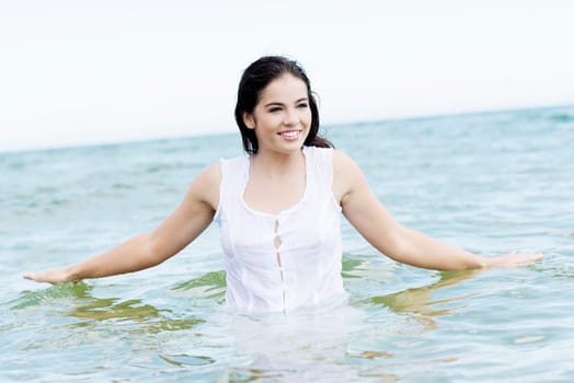 summer happy woman in water,wearing a white dress.
