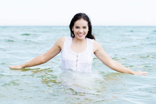 summer happy woman in water,wearing a white dress.