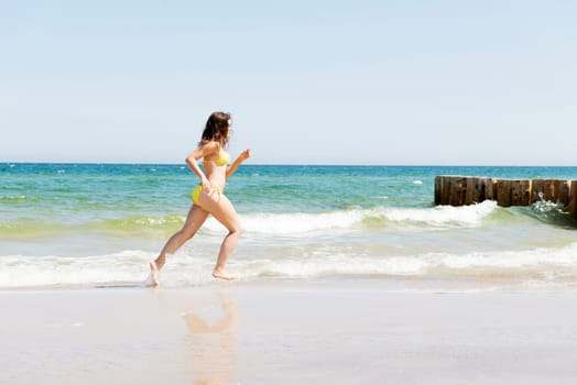 happy woman in bikini running on the beach