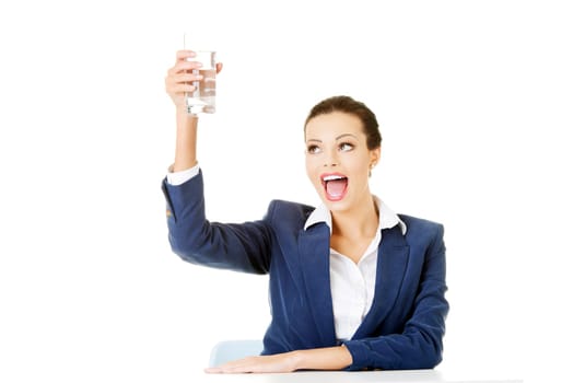pretty business woman sitting at the desk and drinking mineral water from glass
