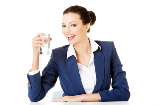 pretty business woman sitting at the desk and drinking mineral water from glass