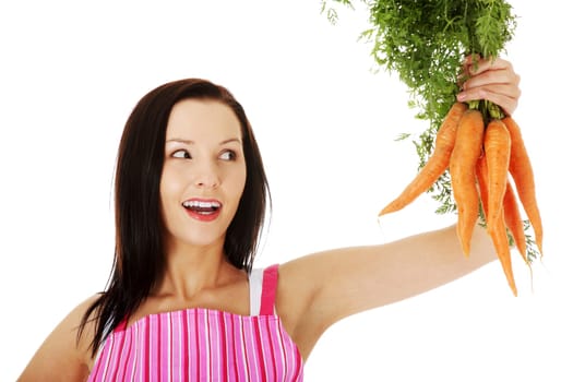 young woman in pink kitchen apron holding fresh carrots