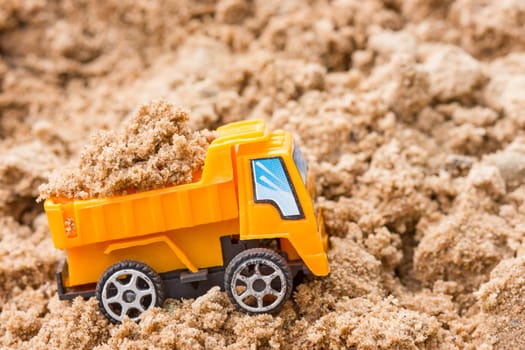 Construction concept. Orange dump truck fully loaded sand