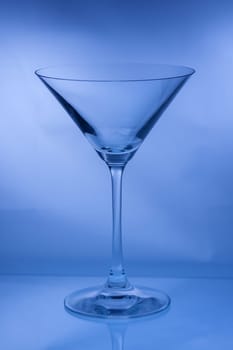 One empty martini glass in a vertical shot in blue tone light