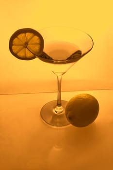 Martini glass with lemon slice and lemon from above in amber light