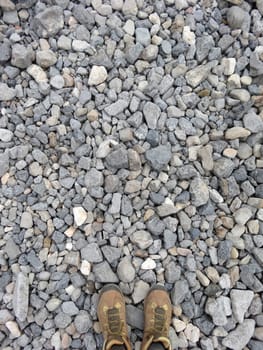 Vertical shot of a pair of hiking boots on gravel from above