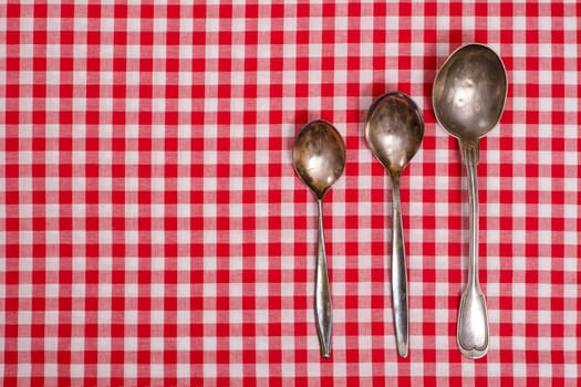 Red white checkered cloth and three old silver spoons