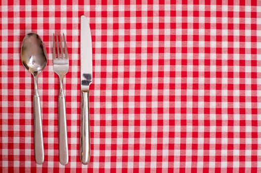 Spoon,knife and fork on a table with checkered cloth