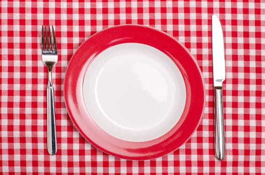 Plate with knife and fork on red and white checkered tablecloth