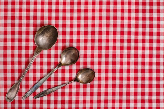 Three silver spoons on table with checkered cloth
