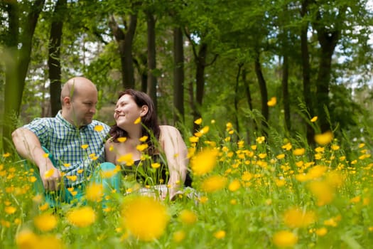 Happy young couple is sitting in a field of buttercups