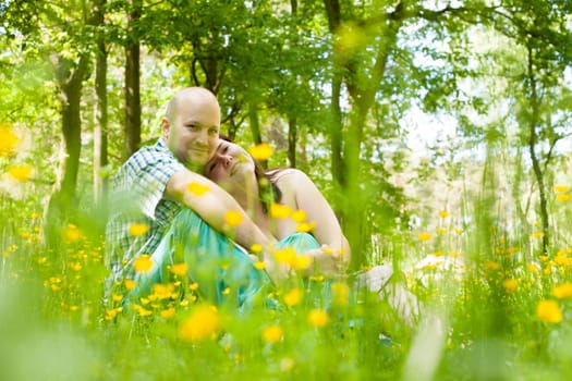 Happy young couple is sitting in a field of buttercups
