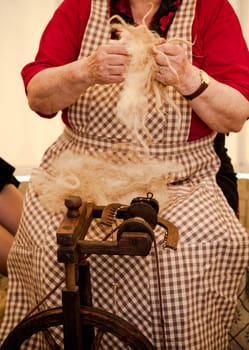 Photo of a elderly woman that spinning wool