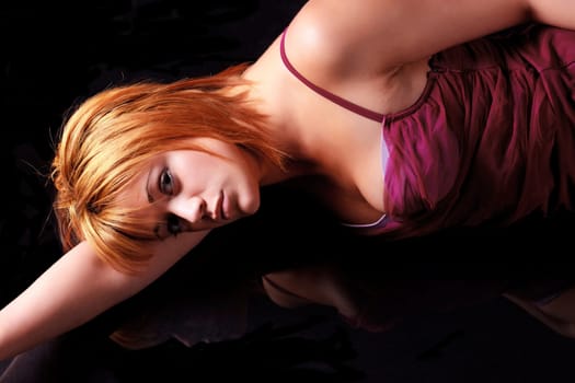 Sensual blonde girl in underwear lie and reflecting on dark background