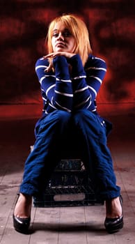 Girl sitting on the stool on red background