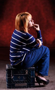 Girl sitting on the stool on red background