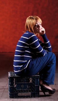 Girl sitting on the stool on red background