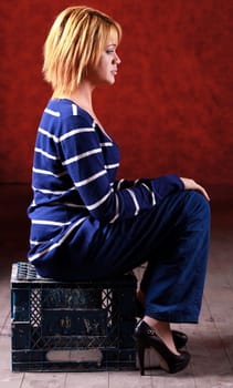 Girl sitting on the stool on red background