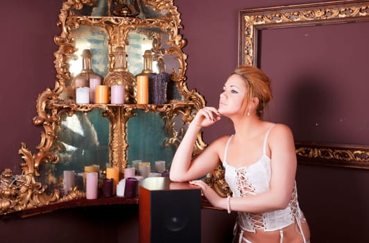 Sensual blonde girl in underwear next to a old mirror