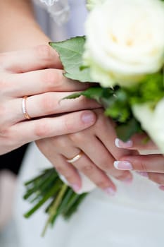 The bride and groom's hands together near wedding bouquet