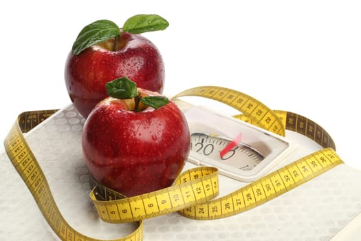 Red apples and a measuring tape over white