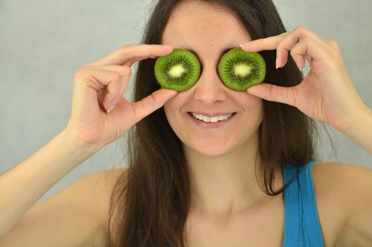 Beautiful young girl is holding kiwi fruit