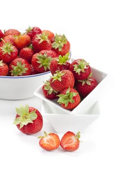 Sugar-sweet strawberries in a white porcelain bowl and an enamel bowl insulated against a white background