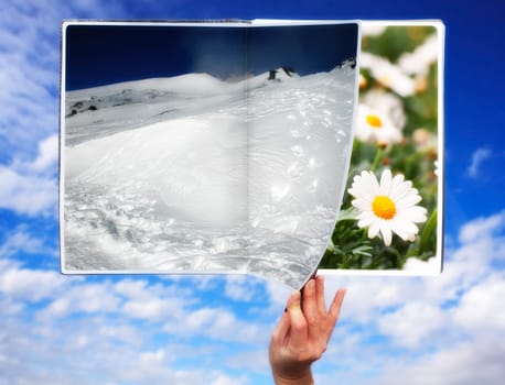 Hand through the book of seasons on cloudy sky