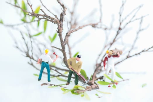 Miniature men working together in felling and cutting trees
