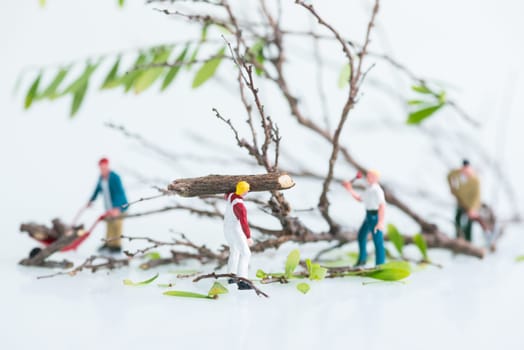 Miniature workmen working together in felling and cutting trees close up
