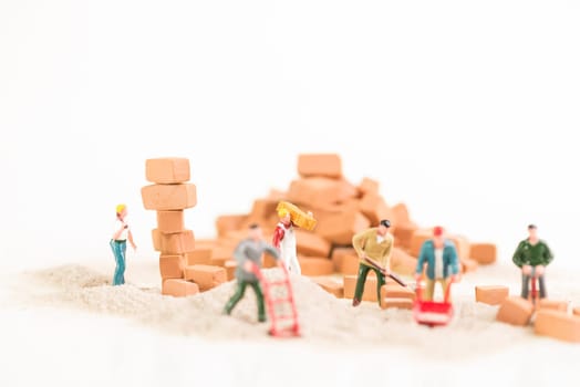 Miniature workmen working together in doing construction brickwork