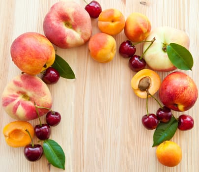 Wooden background with fresh stone fruit,peaches,cherries and apricots
