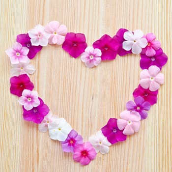 Romantic heart of colorful flowers on wooden background