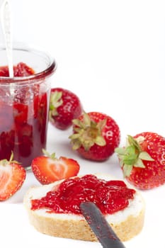 Homemade jam in a jar made from fresh strawberries on a white background