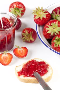 Homemade strawberry jam on white bread on a white background