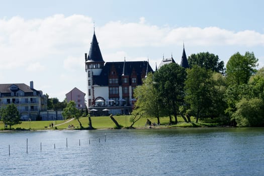 Waren,Mecklenburg Vorpommern/Germany – June 09,2013: Holidaymakers and tourists walk along the promenade of the Schlosshotel Klink on 09 June 2013 in Waren. The castle is a well-known hotel on Lake Mueritz.