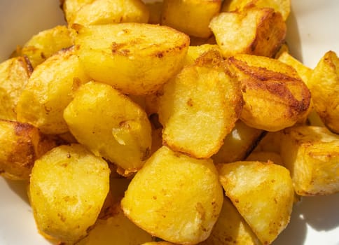Potatoes fried in a frying pan close-up, lying on a white plate, Horizontal view from above, food background.
